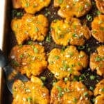 Top down view of 15 golden smashed potatoes on a baking sheet.