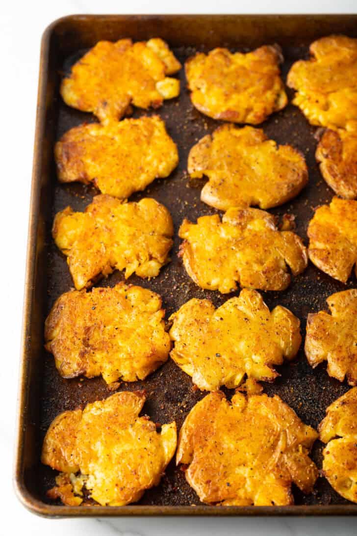 15 golden smashed potatoes on a baking sheet.