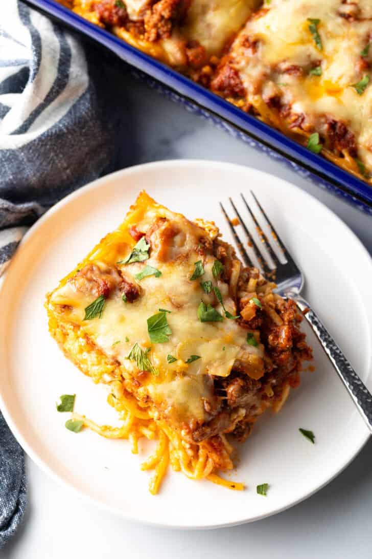 Top down view of a white plate with a serving of spaghetti bake and fork.
