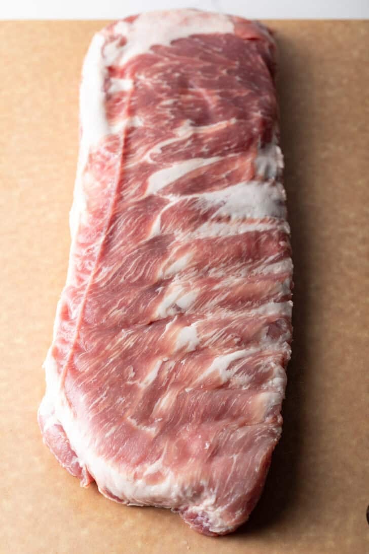 Overhead shot of a raw rack of pork ribs on a cutting board.