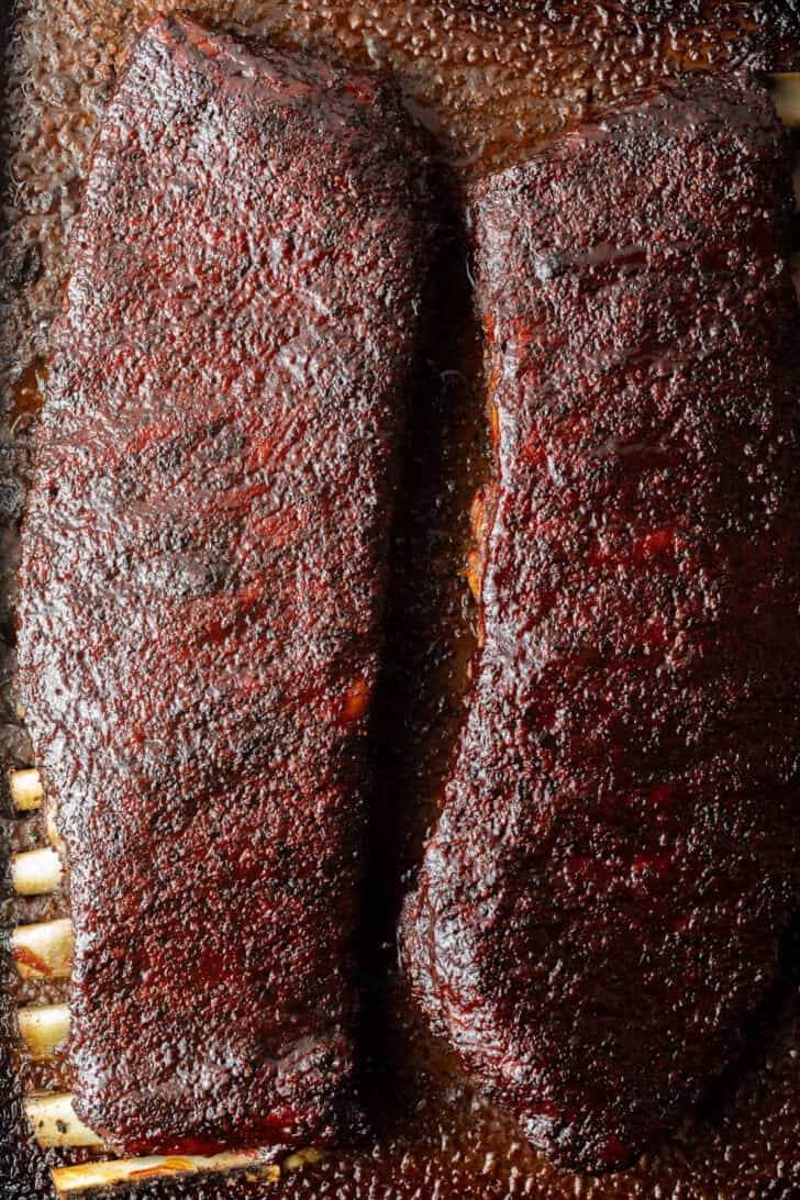 Two full racks of St Louis pork ribs on cooking tray.