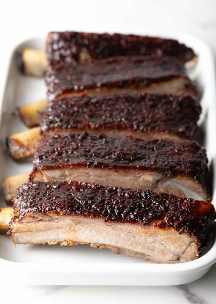 Six barbecue pork ribs sliced on a white tray.