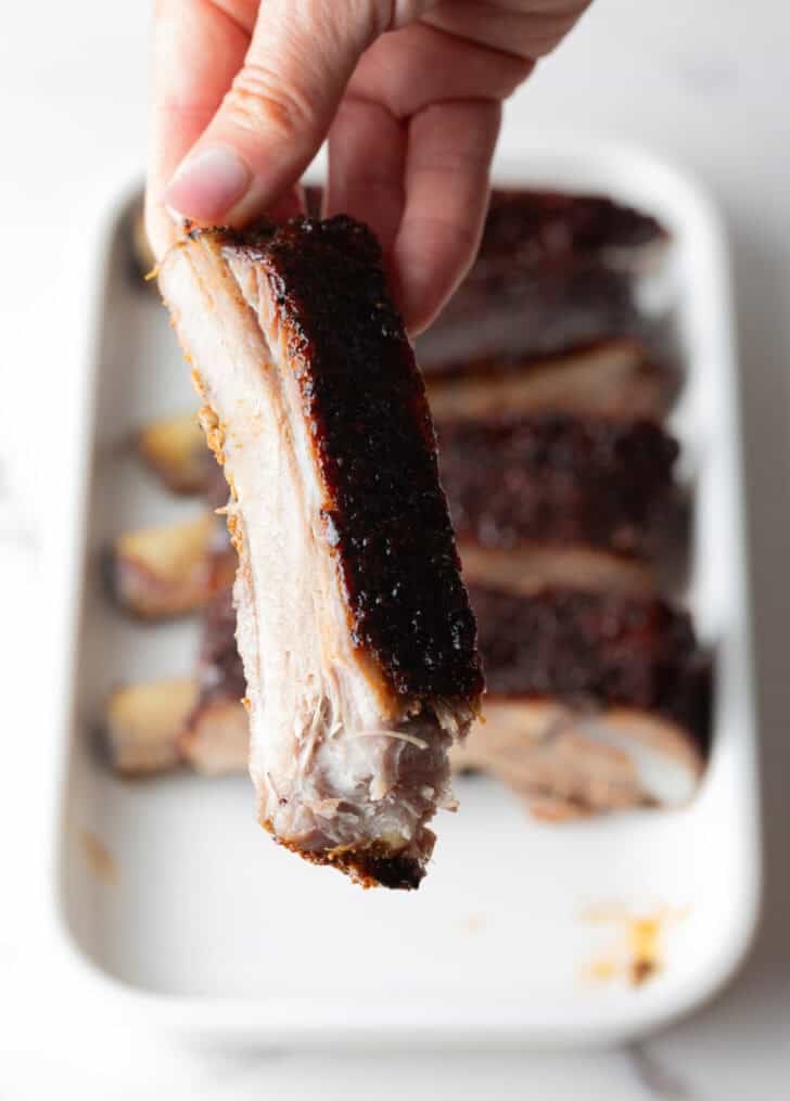 Shot of single St. Louis rib being held up close to camera.