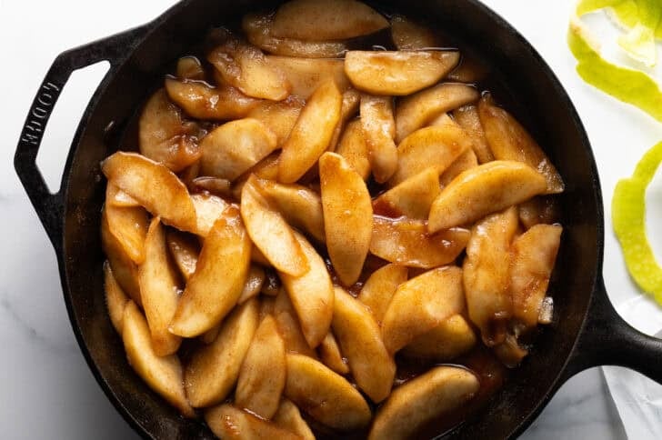 Fried apples with cinnamon in a large cast iron skillet.