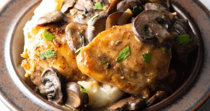 Mushroom Chicken Recipe on dark plate with creamy mashed potatoes and mushroom gravy.