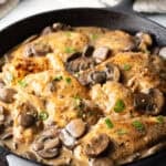 Mushroom Chicken - Cast iron brimming with seared chicken breast pieces and sliced mushrooms in a brown gravy.