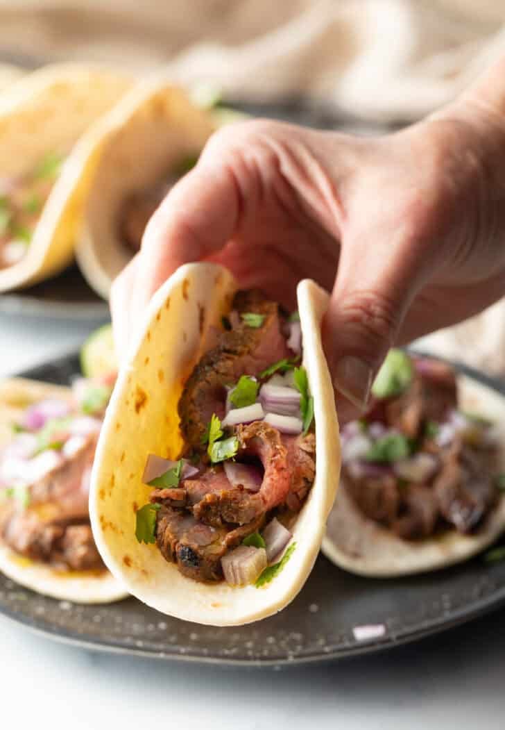 Hand holding a taco with marinated steak.