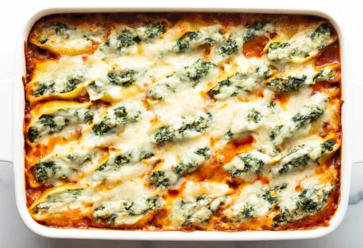 Top down view large rectangle baking dish with spinach and meat stuffed shells.