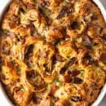 Overhead shot of croissant breakfast casserole recipe in a white baking dish, fresh from the oven.