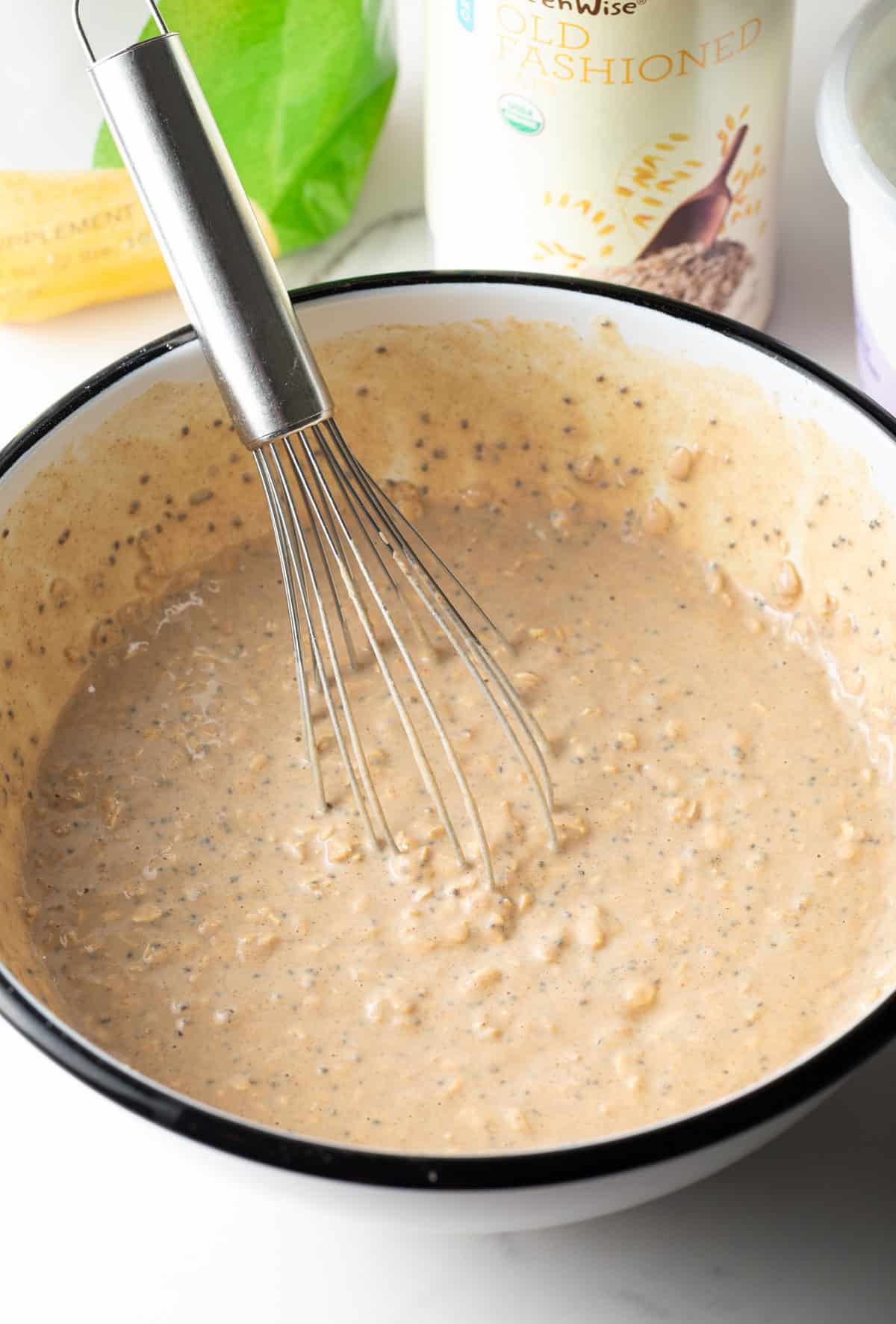 A whisk stirring all ingredients for high protein overnight oats.