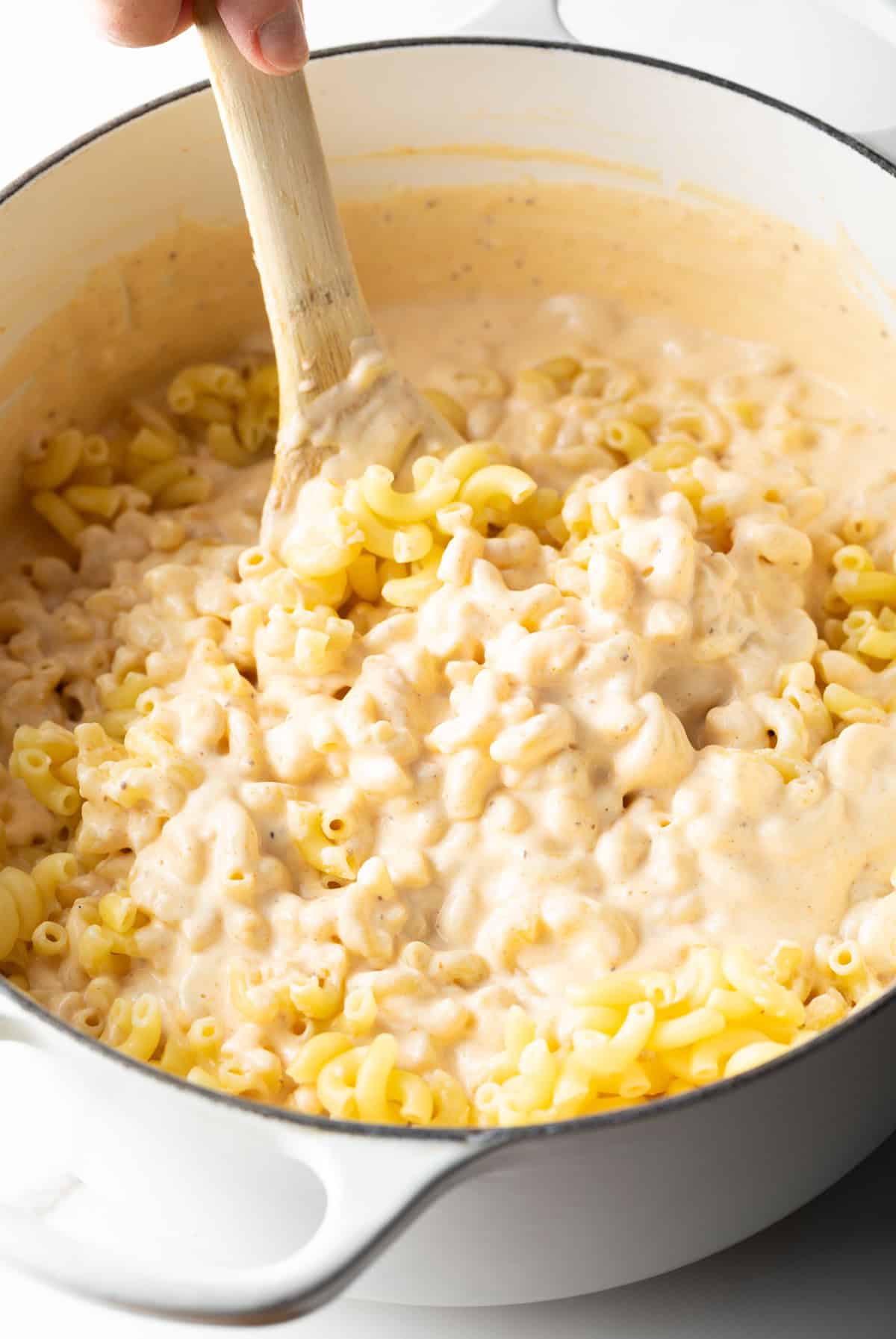 Macaroni pasta is being stirred into the cheese sauce for lobster mac and cheese.