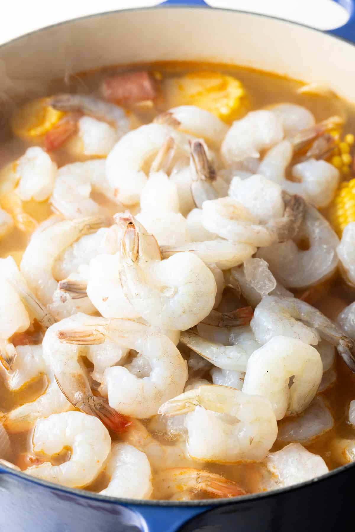 Raw shrimp is being added to the pot for low country shrimp and sausage boil recipe.