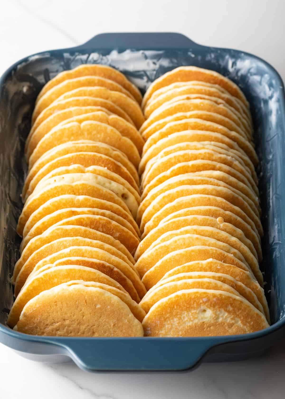 Halved pancakes in two rows in a blue baking dish.