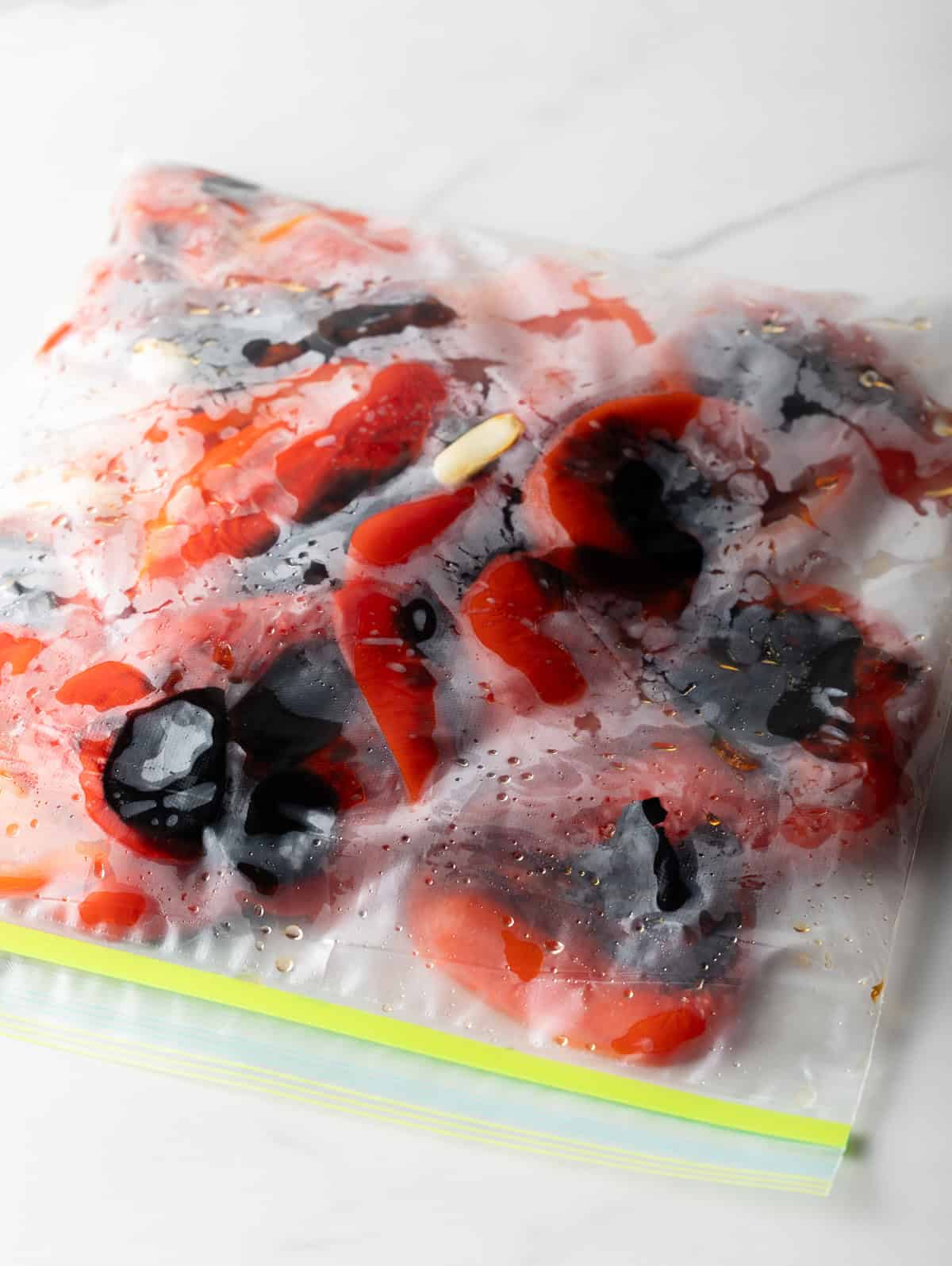 Charred red peppers steaming inside of a ziplock bag.