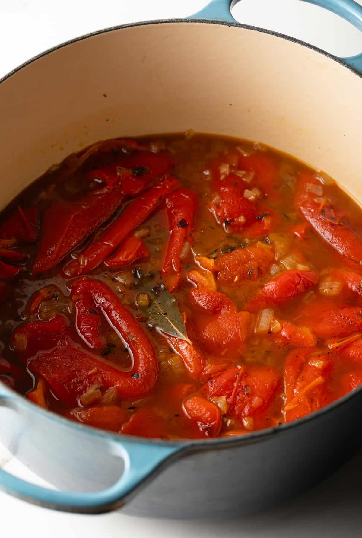 Roasted red peppers, broth, and herbs in a pot of what will become roasted red pepper soup.