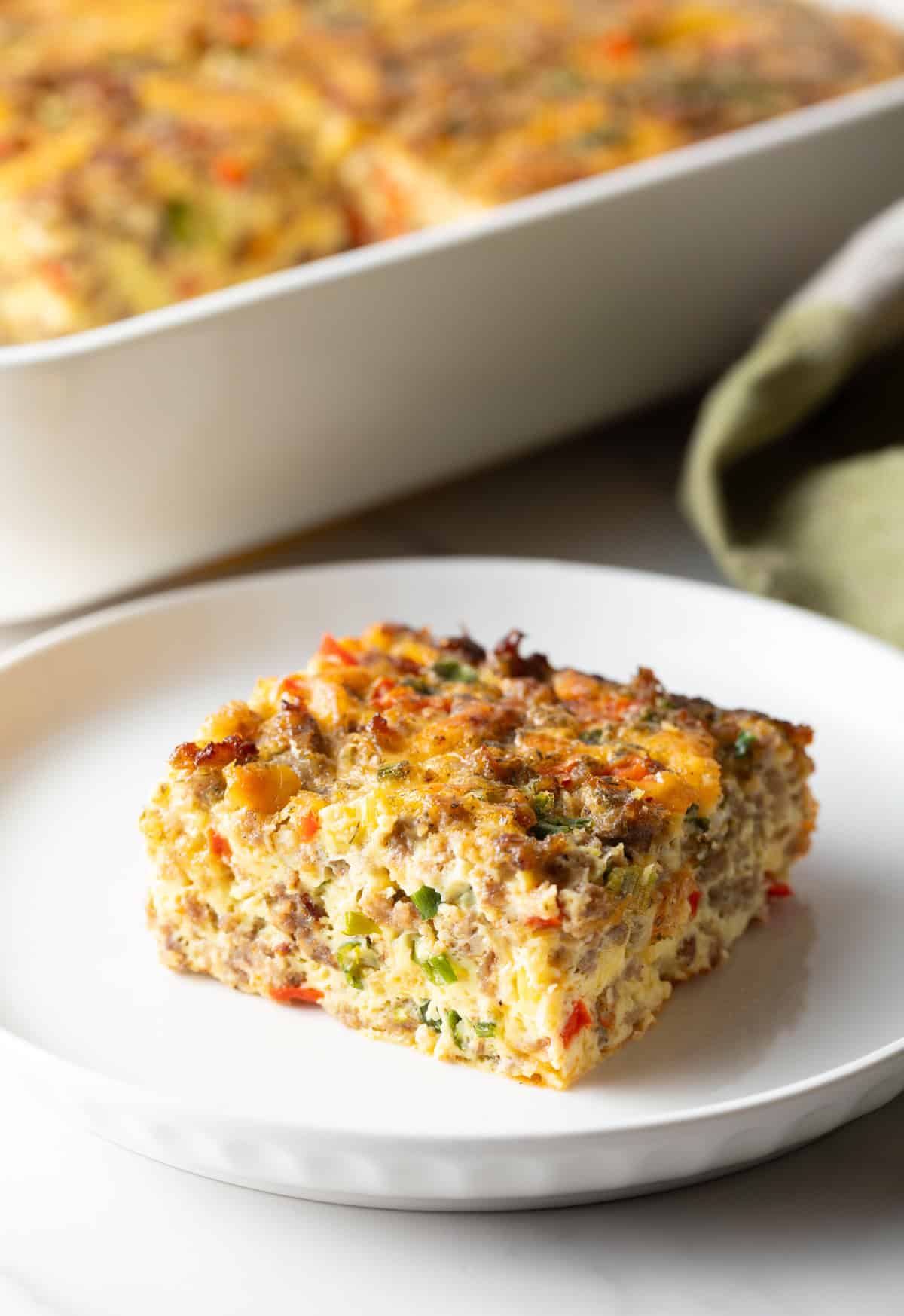 Square of sausage breakfast casserole on a white plate.