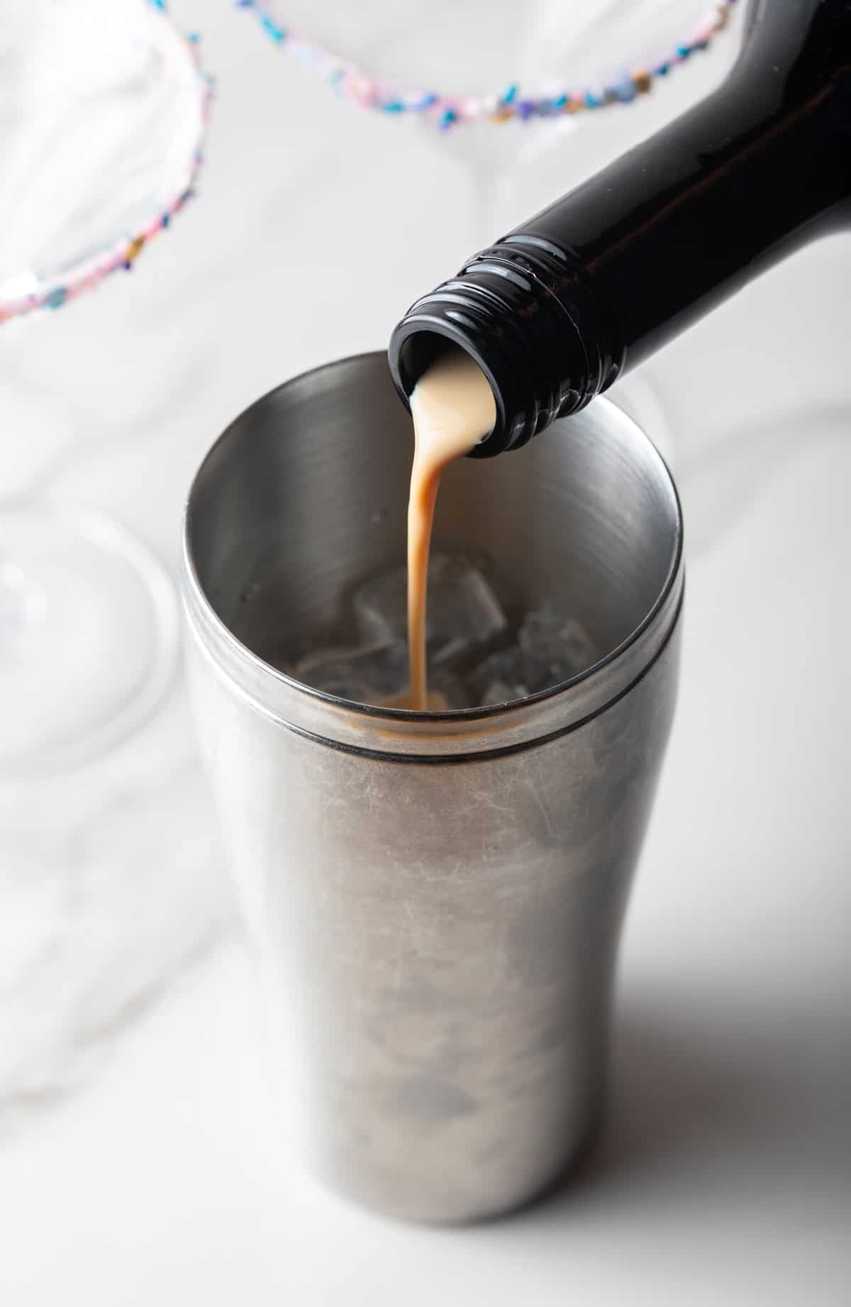 Bailey's Irish Cream being poured into a cocktail shaker.