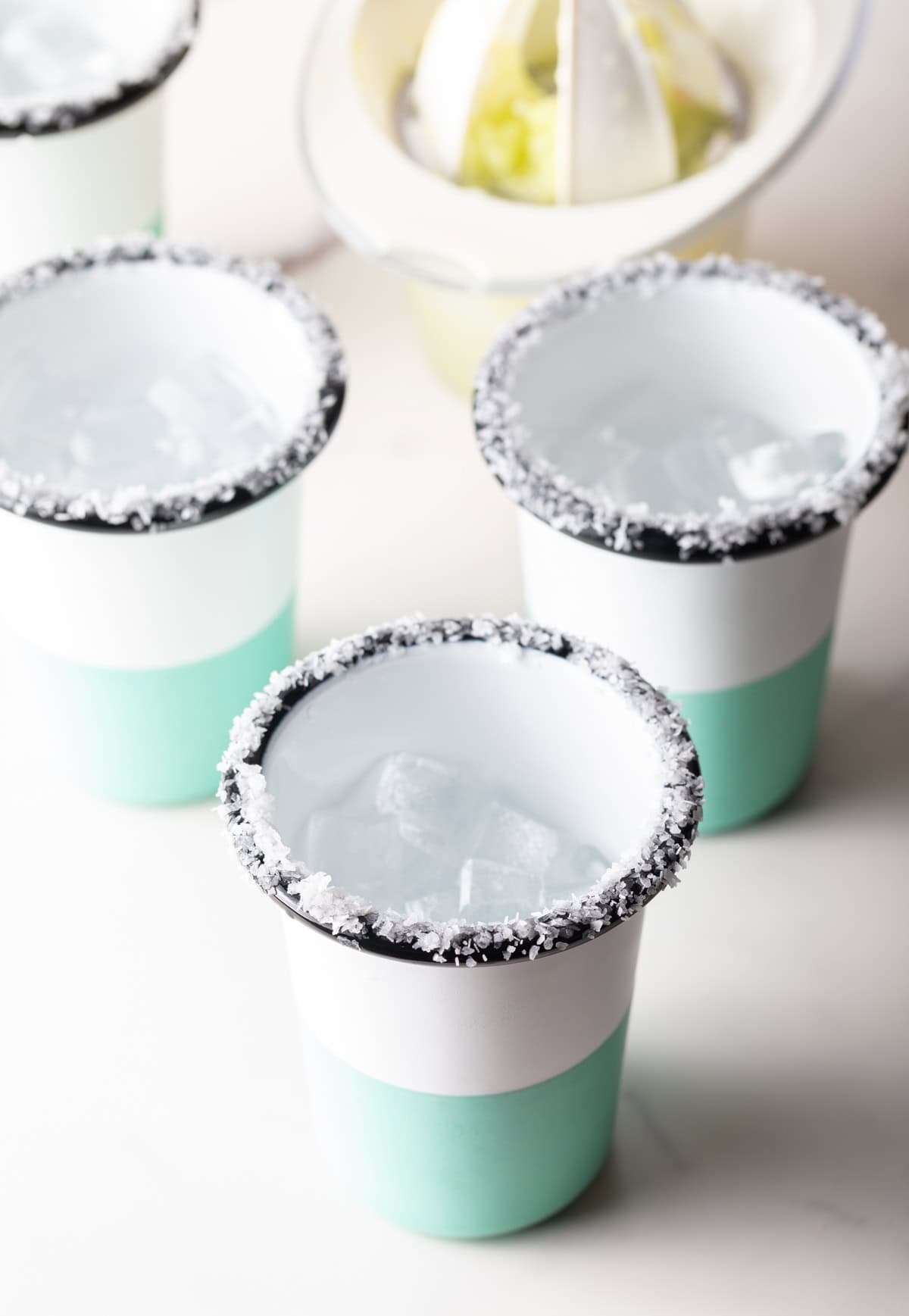 4 blue and white striped cups, with salt around the rim.