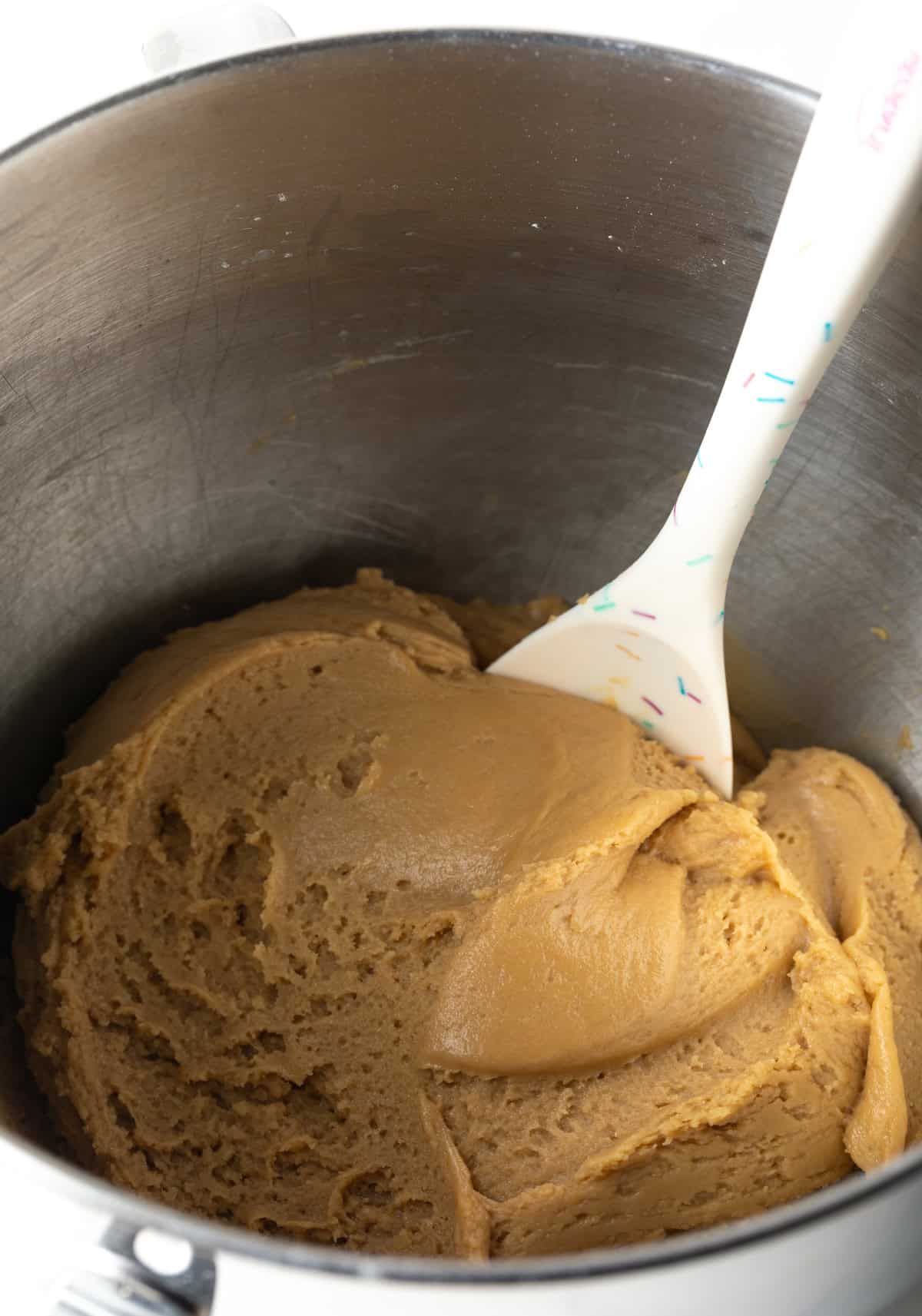 Brown sugar cookie dough in a metal mixing bowl with a spatula.