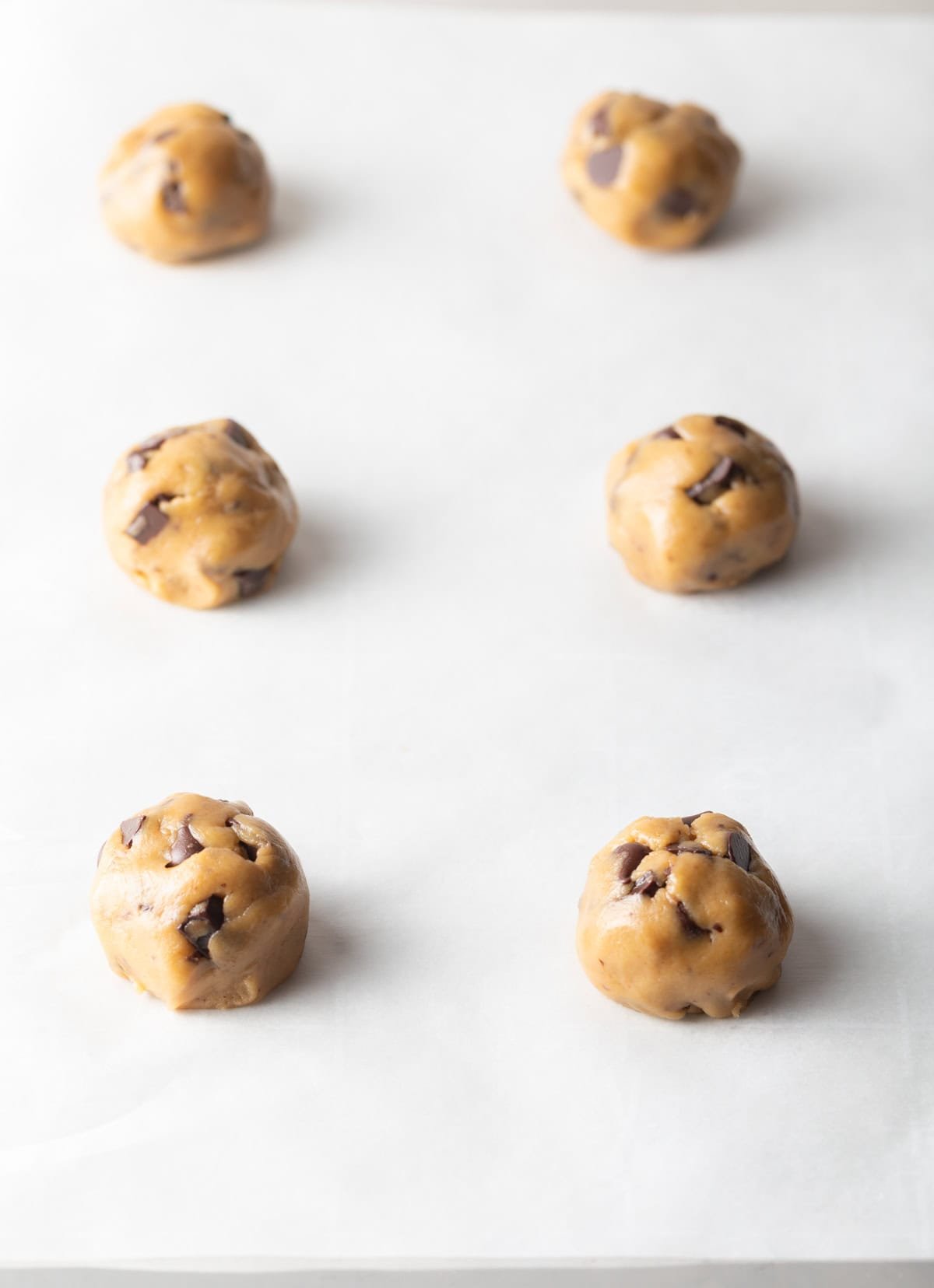 6 balls of cookie dough on a baking sheet.