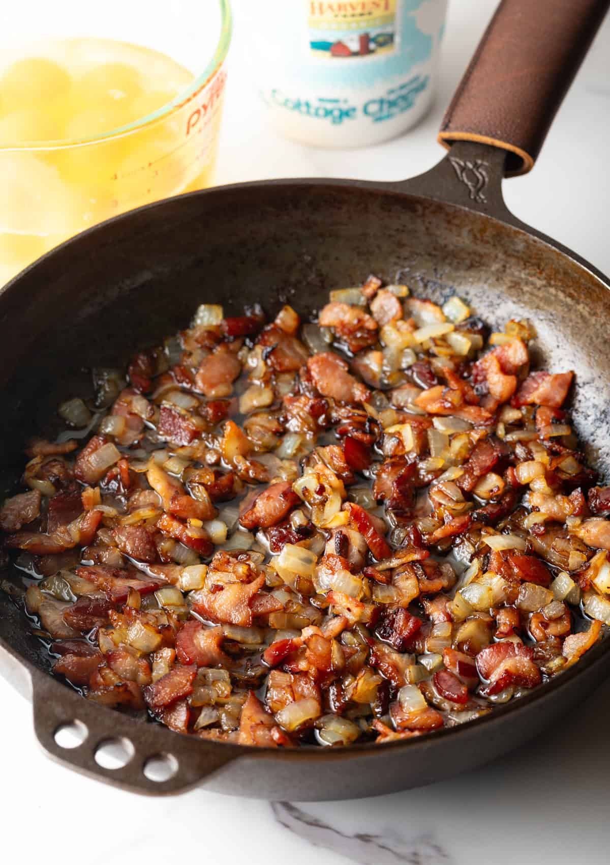 Cooking chopped bacon and onions in a cast iron skillet.