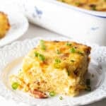 Square serving of hash brown potato, egg and cheese casserole on a white plate.