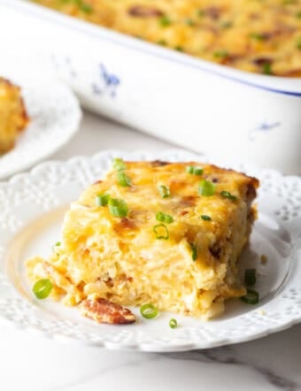 Square serving of hash brown potato, egg and cheese casserole on a white plate.