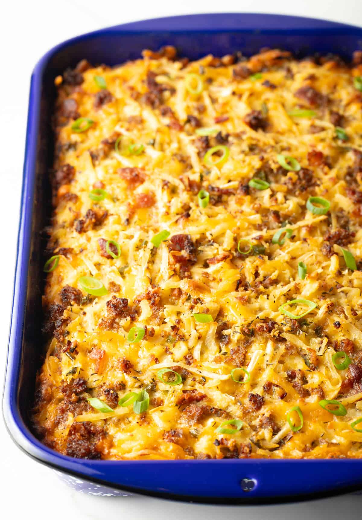 A freshly baked breakfast casserole with hash browns in a blue baking dish.