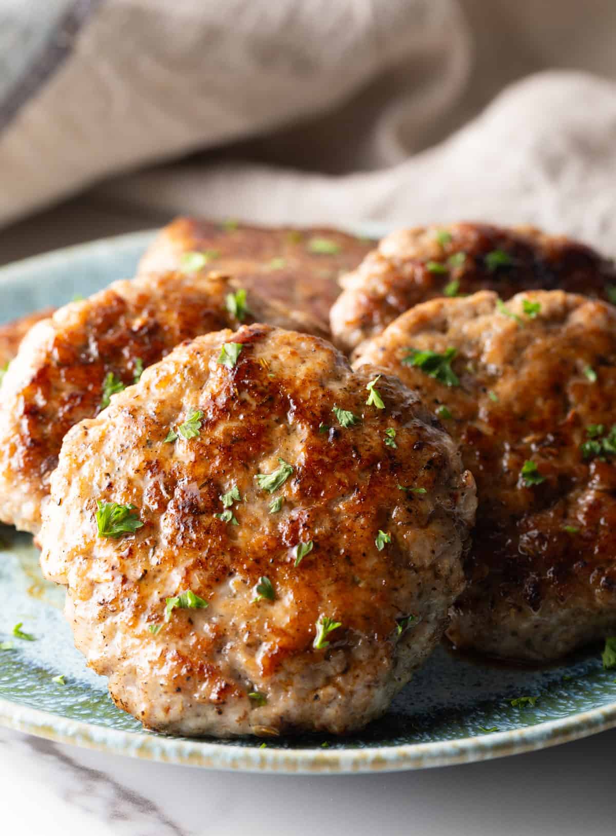 Slices of an easy homemade breakfast sausage recipe lined up in a circle on a blue plate.