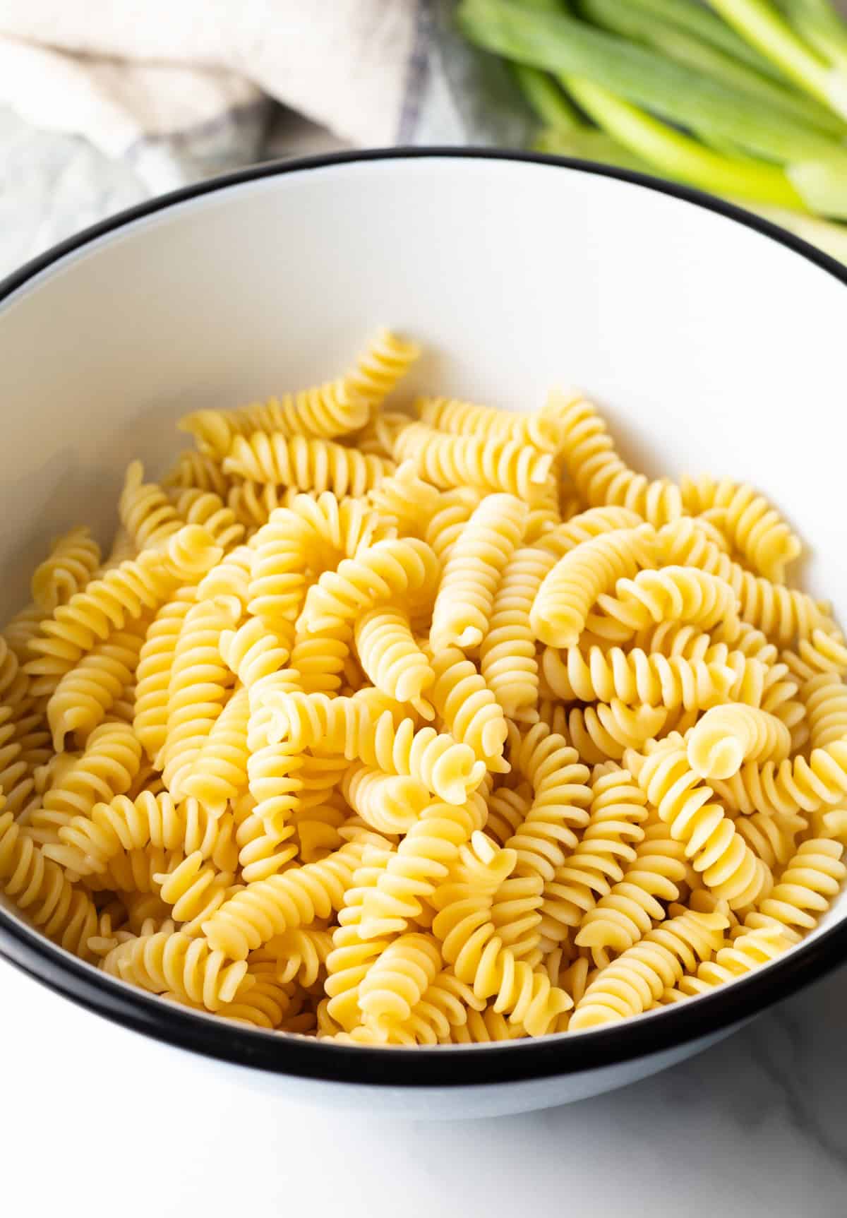 Cooked fusilli pasta in a white bowl.
