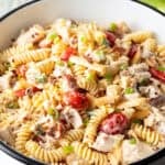 A white bowl filled with a chicken bacon ranch pasta salad with bacon and fusilli.