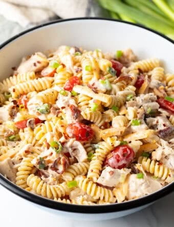 A white bowl filled with a chicken bacon ranch pasta salad with bacon and fusilli.
