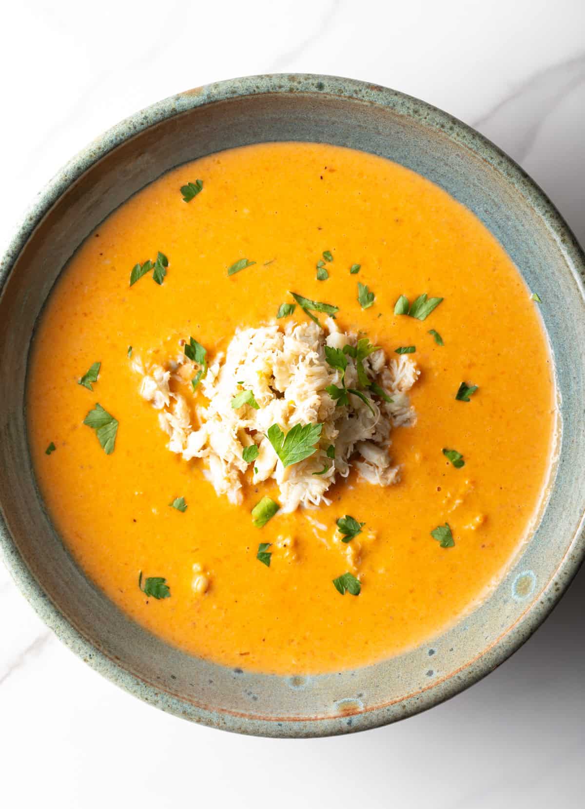 An overhead shot of a crab bisque recipe in a black bowl.