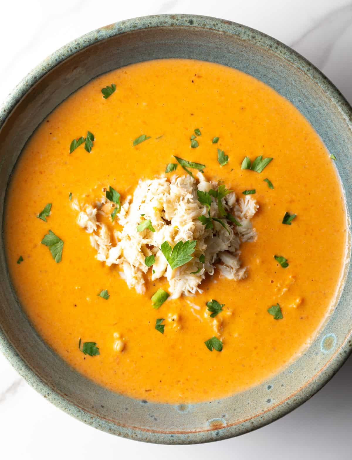An overhead shot of a crab bisque recipe in a grey bowl.