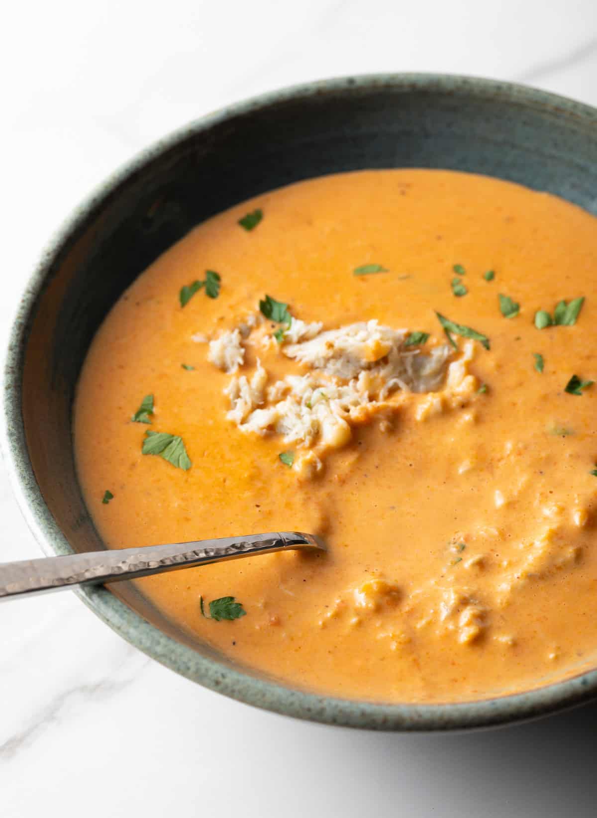 A bowl of easy crab bisque soup with a metal spoon in the bowl.