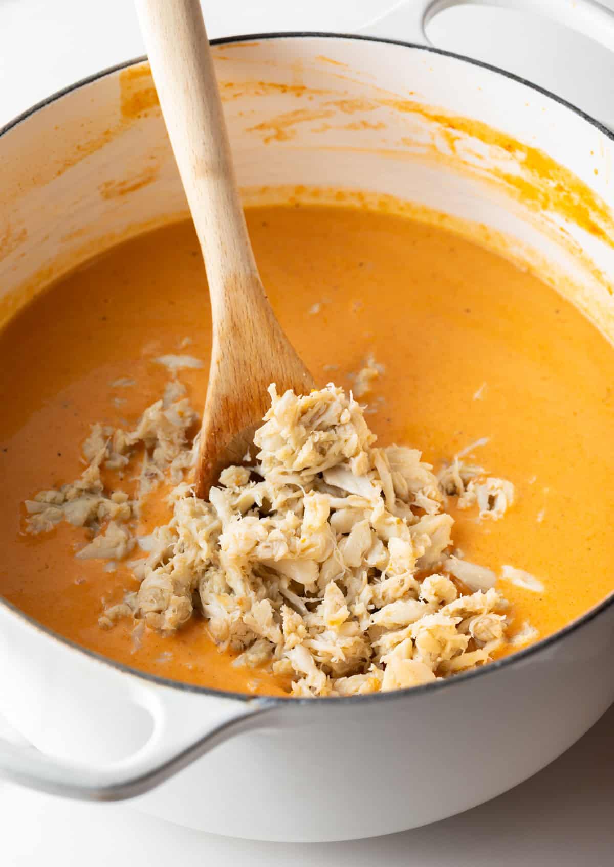 Crab meat is being added to a crab bisque soup recipe.