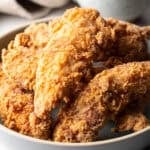 Crispy deep fried chicken tenders sitting in a white bowl.