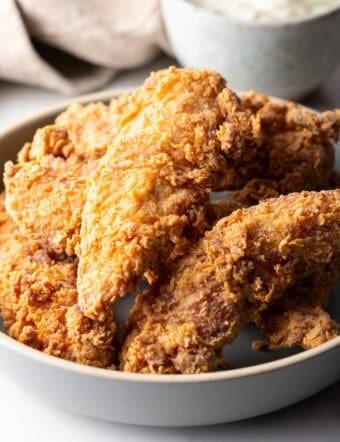 Crispy deep fried chicken tenders sitting in a white bowl.