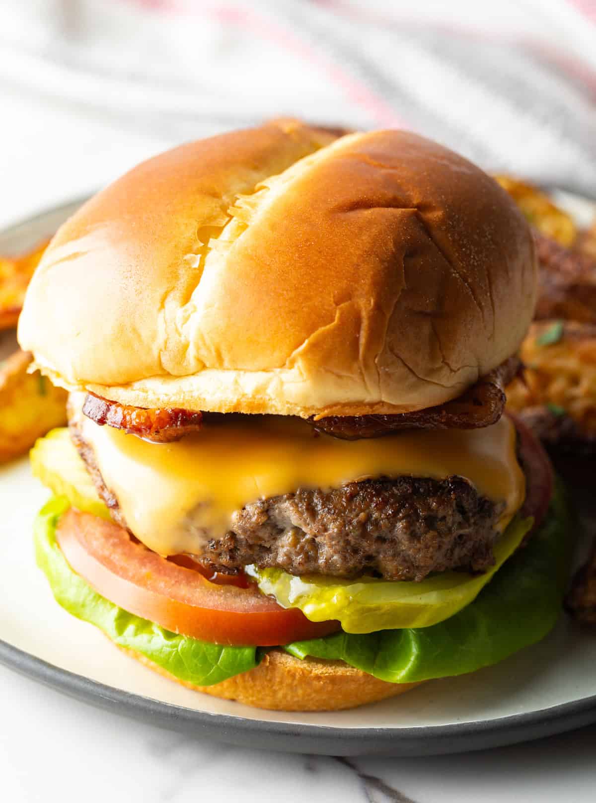 A juicy deer burger recipe featuring a deer burger patty between two buns and topped with cheese and condiments.