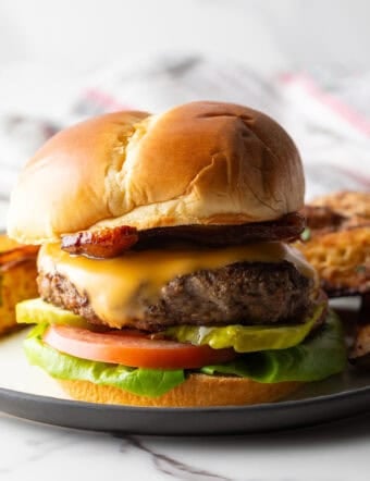 A juicy deer burger recipe featuring a deer burger patty between two buns and topped with cheese and condiments.