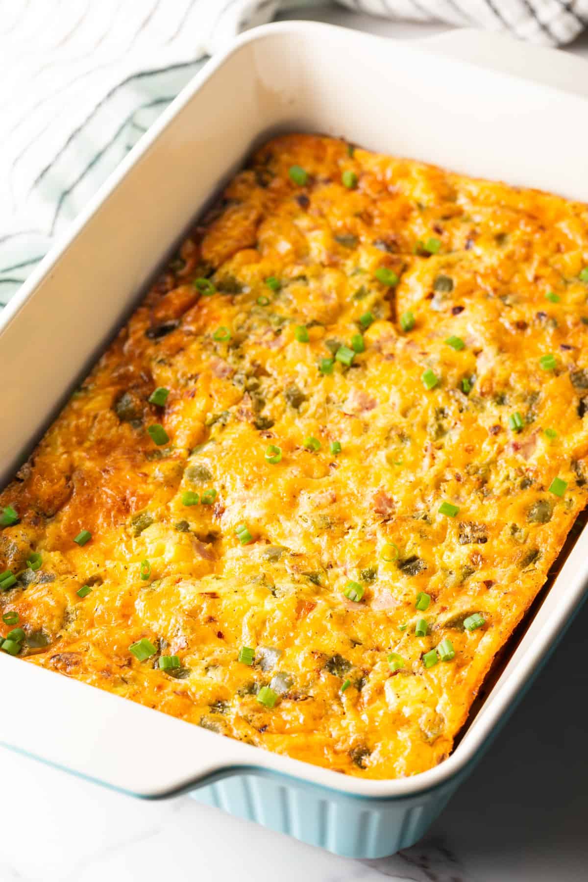 A freshly baked Denver omelette casserole in a white baking dish.