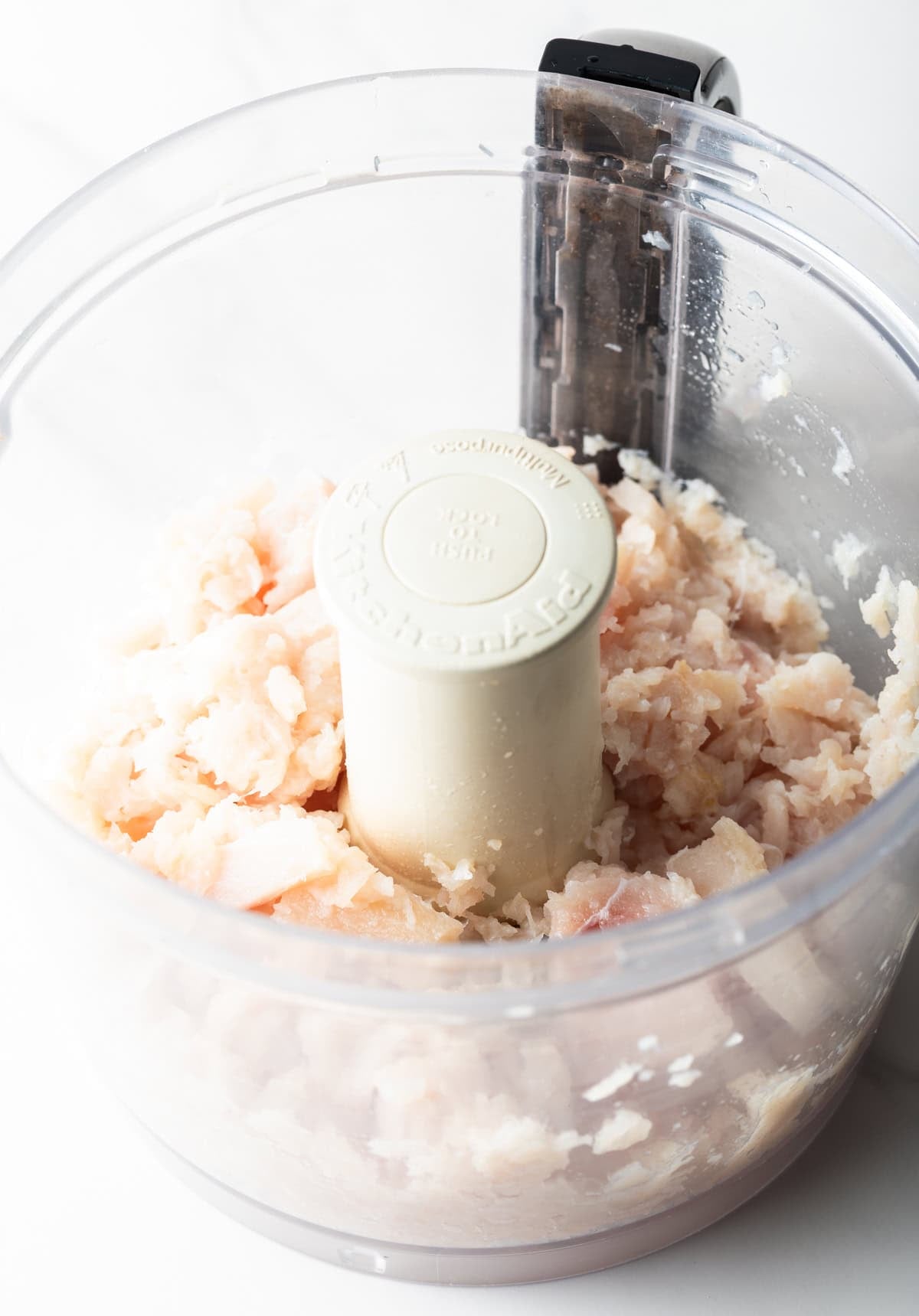 Raw fish is being pulsed in a food processor to make fish patties.