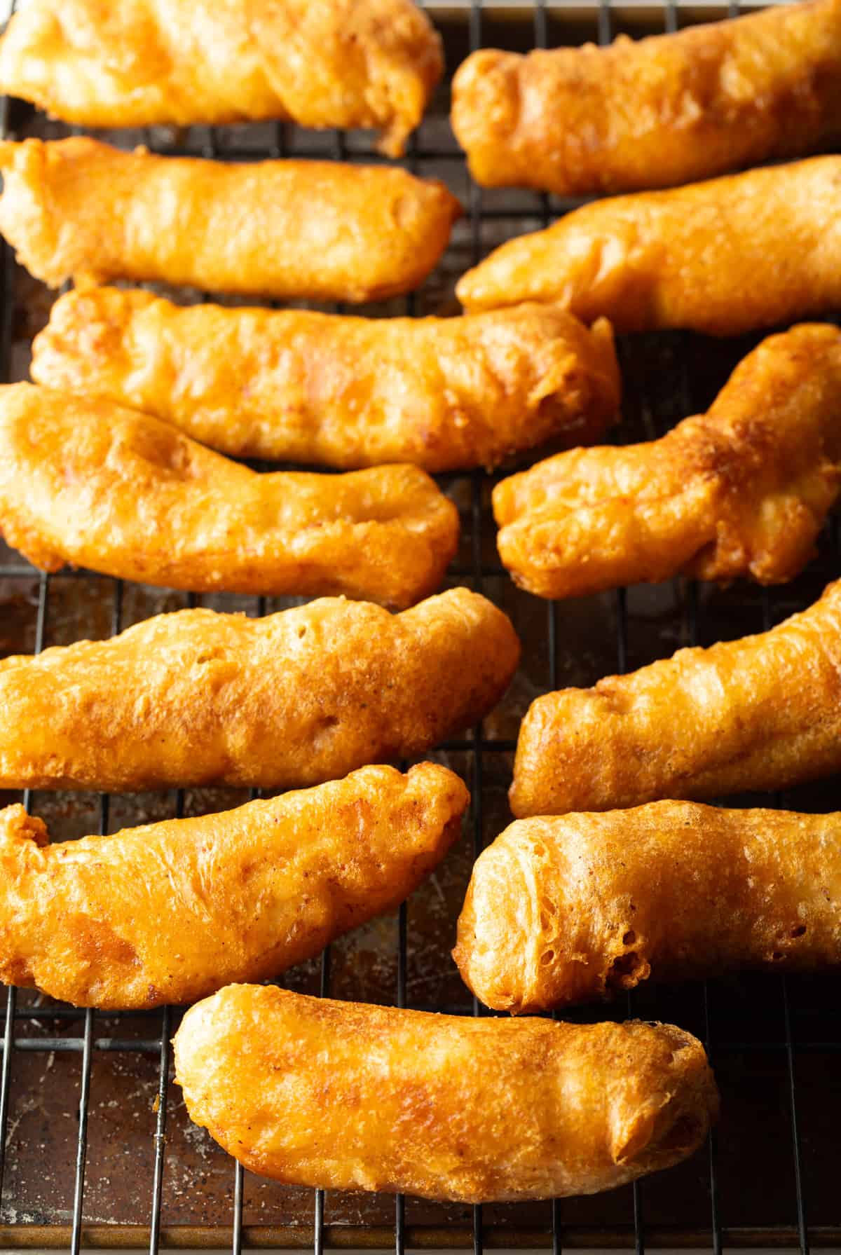 Crispy fried fish pieces sitting on a draining rack.