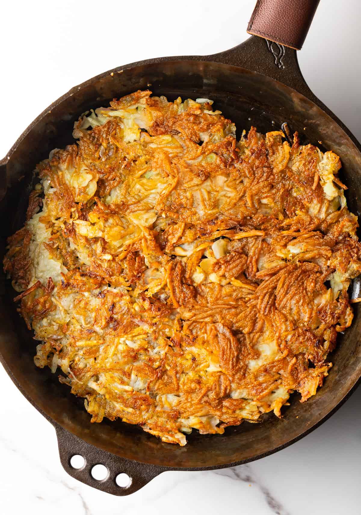 Crispy homemade hashbrowns in a black skillet.