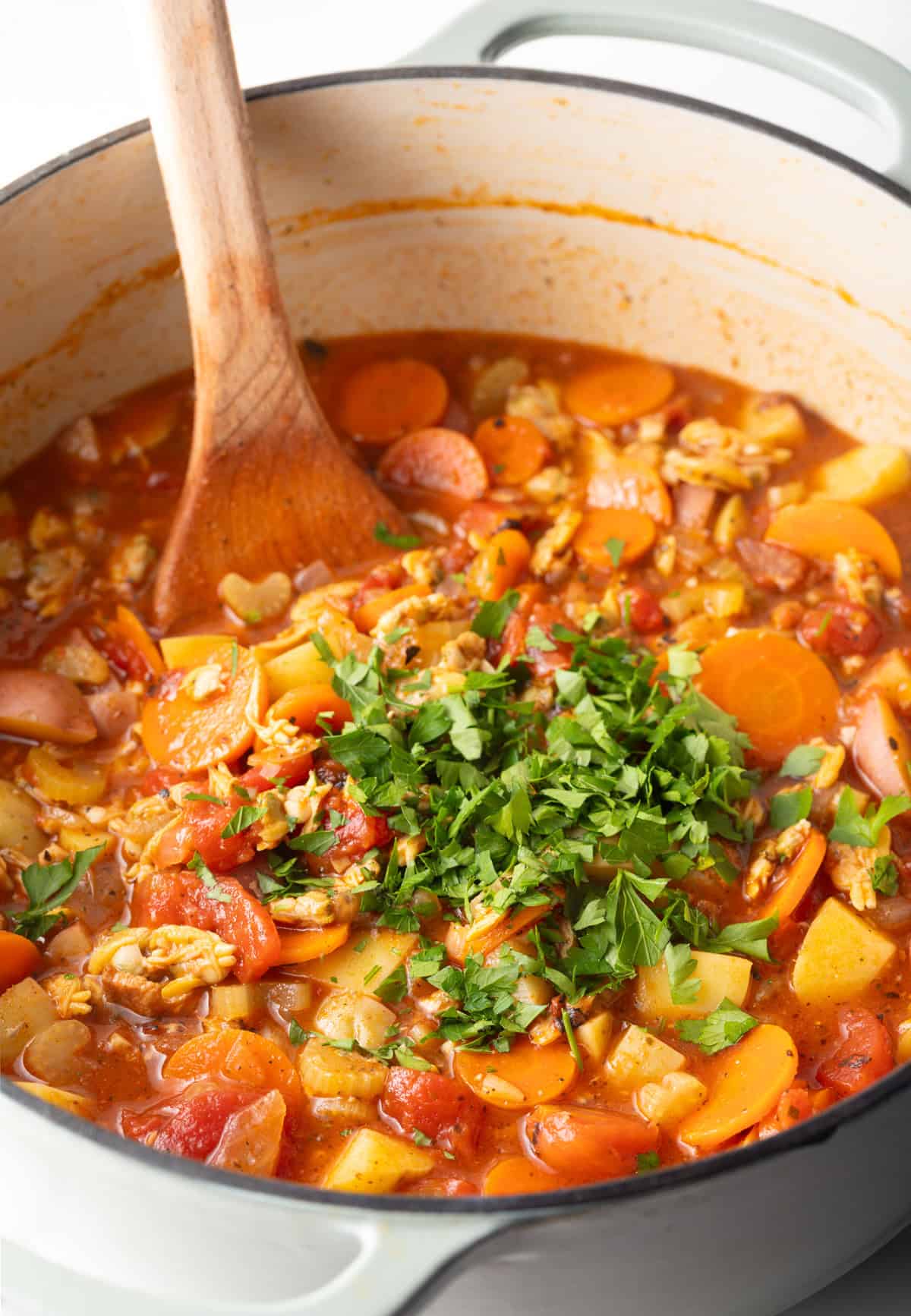Fresh parsley is being added to a pot of a Manhattan-style clam chowder recipe.