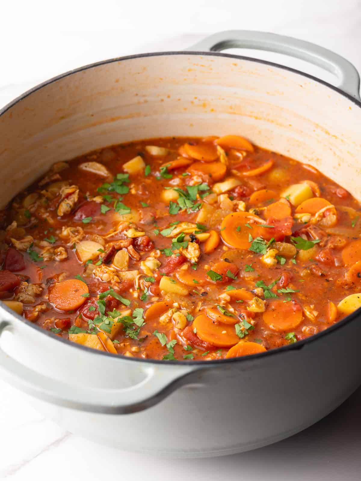A pot of ready-to-serve Manhattan clam chowder topped with fresh parsley.