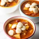 Three white bowls filled with a Manhattan clam chowder recipe topped with oyster crackers.