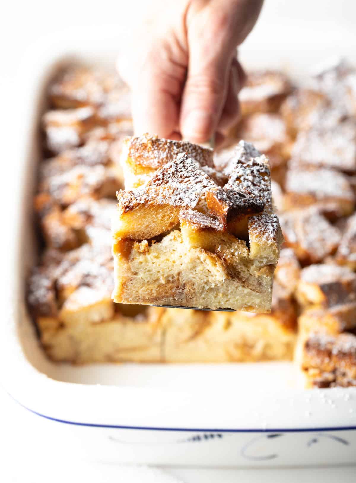 Hand with square of casserole to camera.