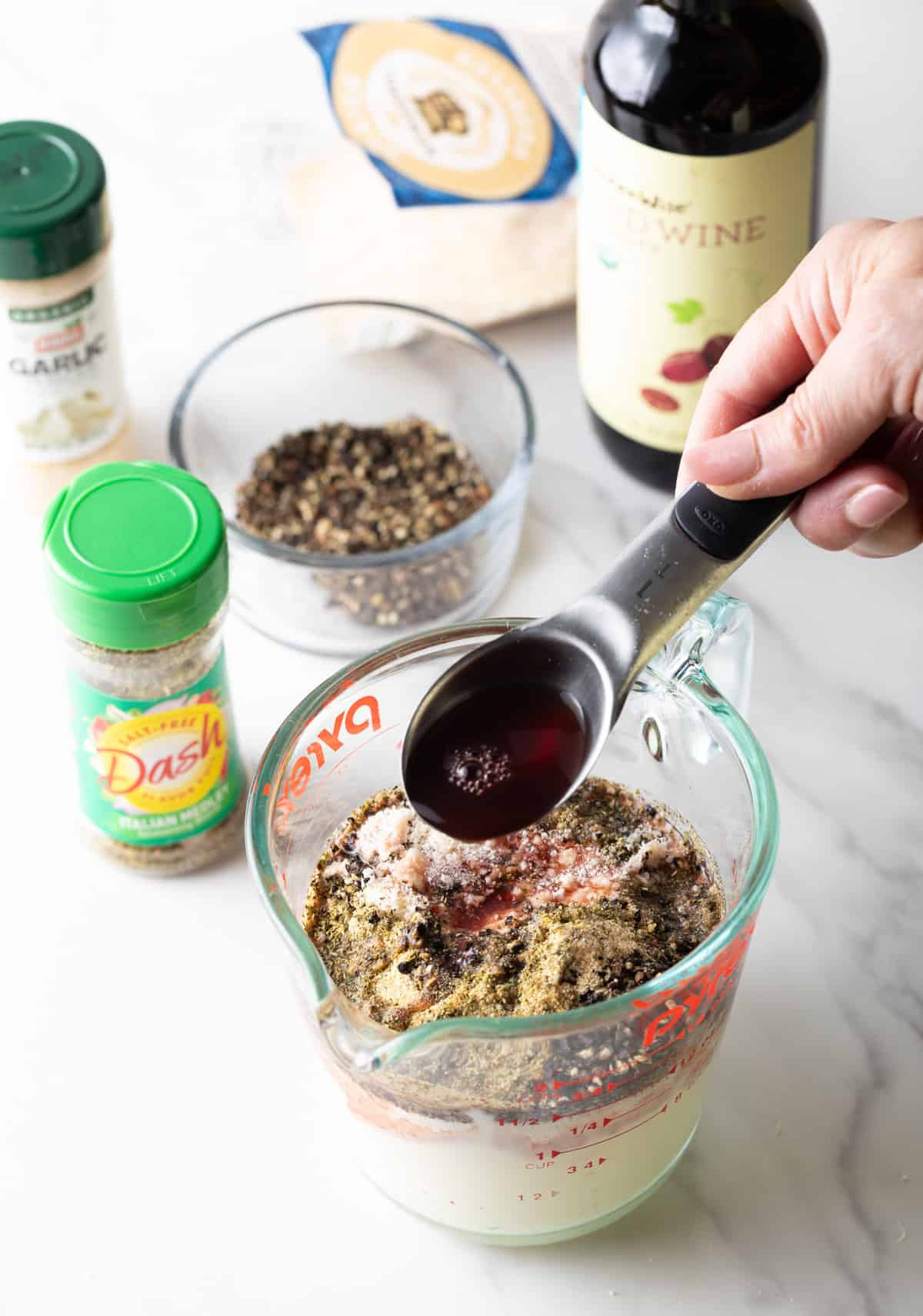 Red wine vinegar is being added to the peppercorn parmesan salad dressing.