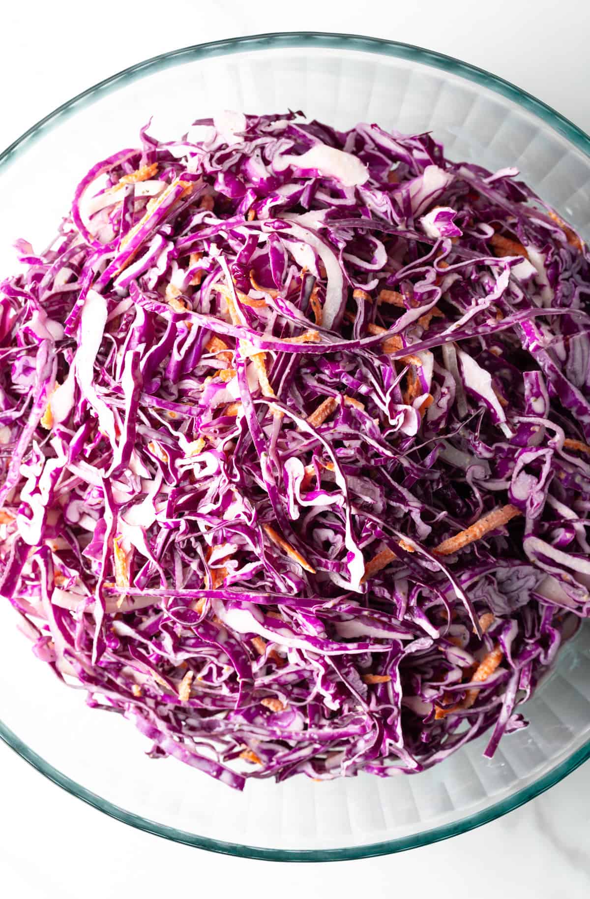 Overhead shot of a red cabbage slaw recipe in a glass bowl.